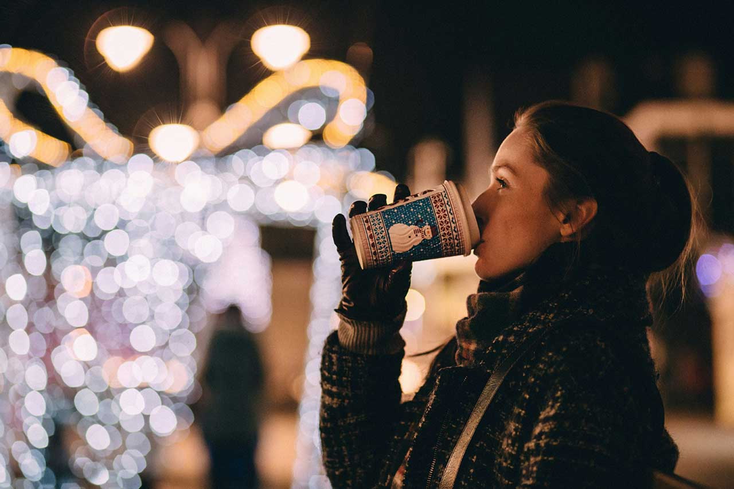 Frau trinkt aus einem Weihnachtsbecher